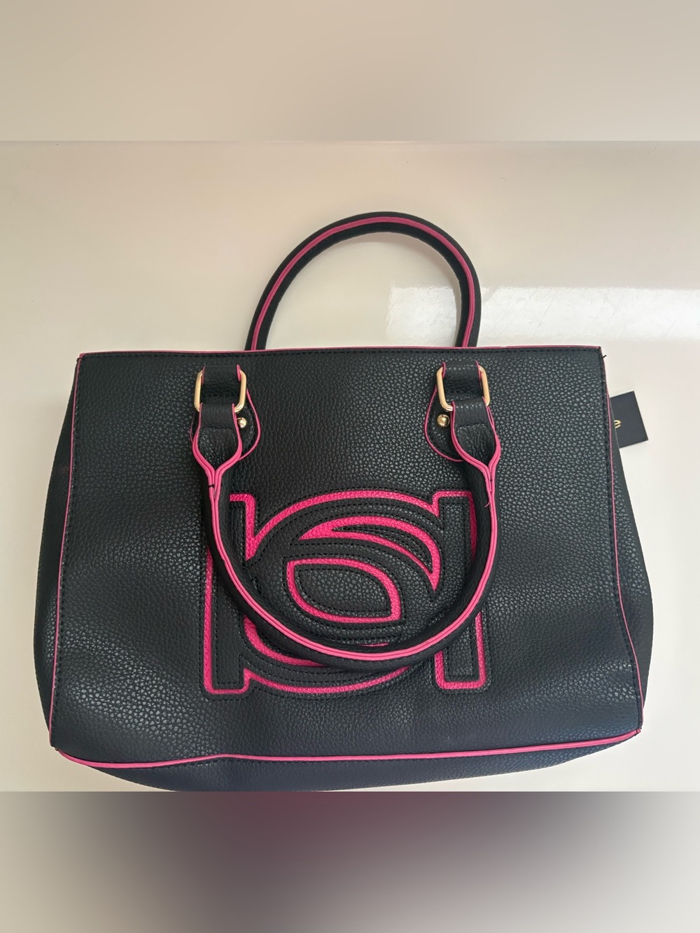 NWT Bebe black faux leather satchel with hot pink trim and a large embossed logo
